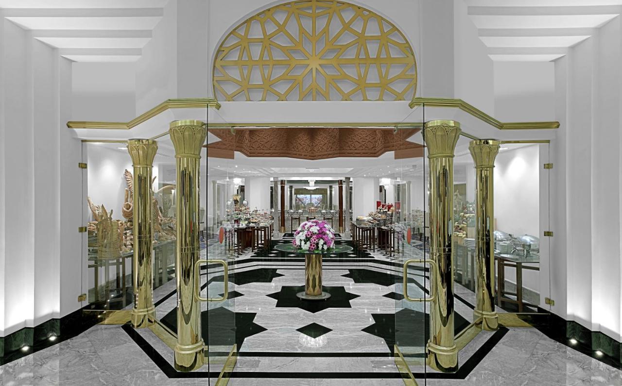 Makkah Hotel La Meca Exterior foto The photo shows an elegant interior space, likely a luxury retail or boutique environment. It features a grand entrance with large glass doors framed by ornate golden pillars. The design includes intricate geometric patterns, particularly in the arch