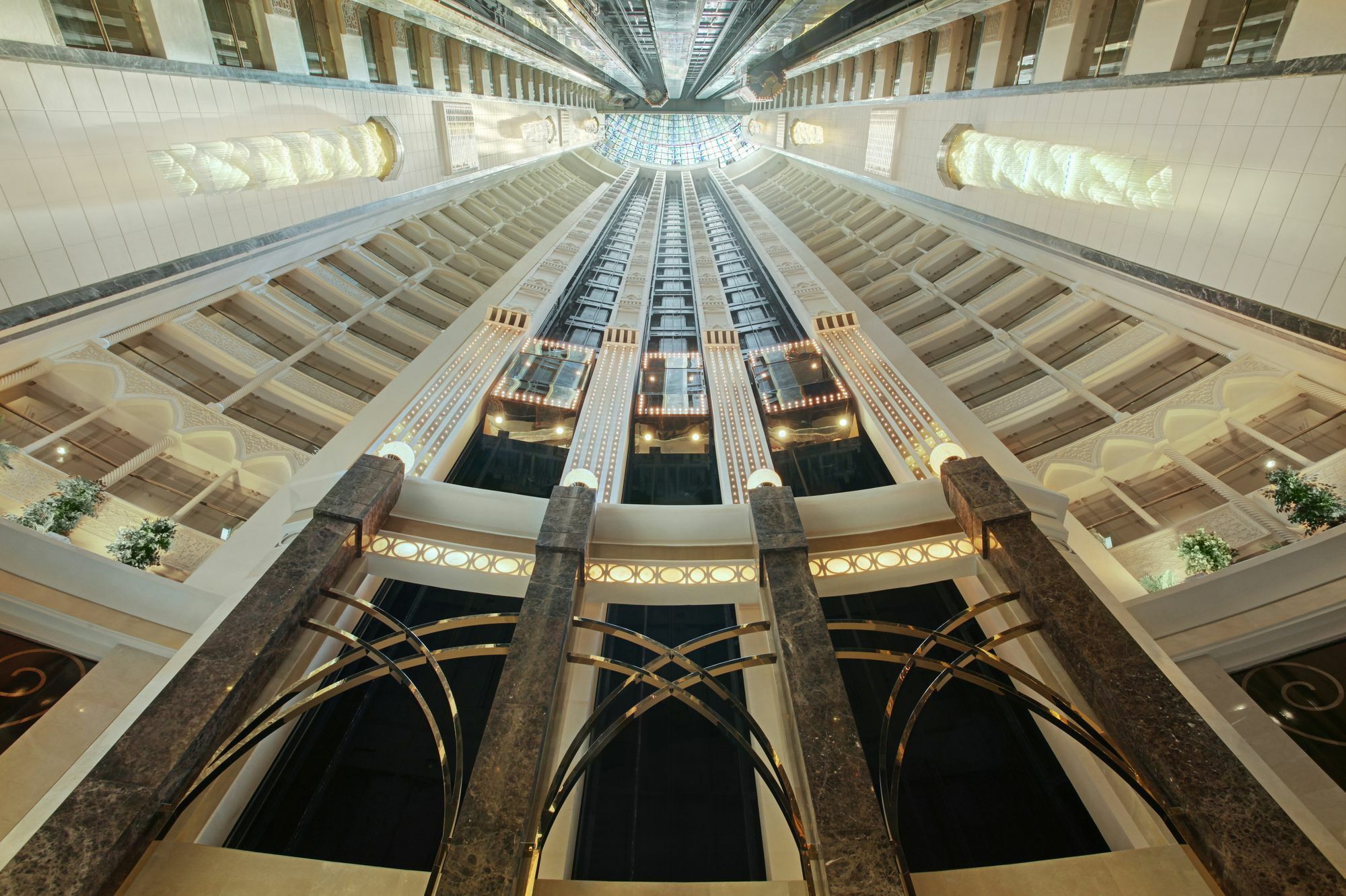 Makkah Hotel La Meca Exterior foto The photo depicts a view looking upward inside a tall, modern atrium of a building. The architectural design features sleek lines and a combination of marble and glass elements. Tall, polished columns are visible, and multiple floors rise high above,